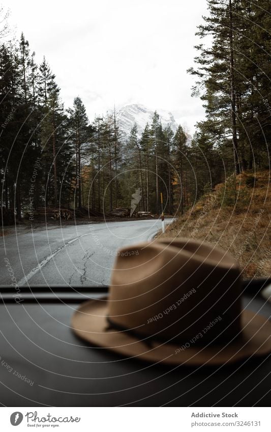 Hat inside a car at lonely highway amid mountains route sky cloud travel tourism landscape road asphalt journey tree season beautiful scenic freedom forest