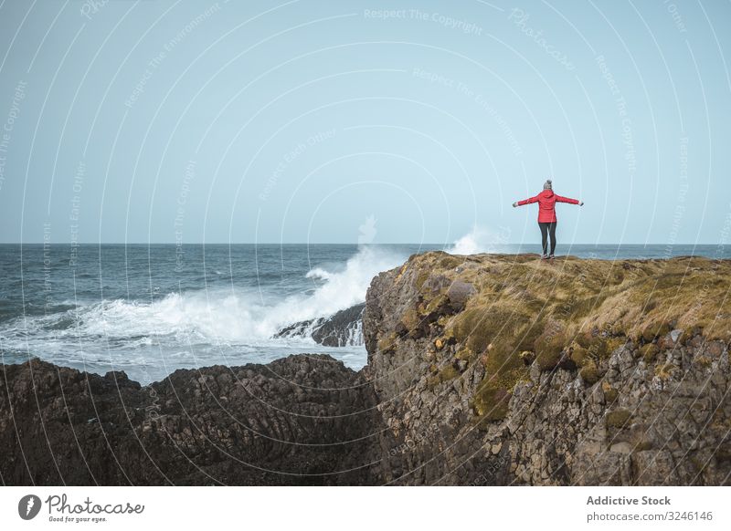 Woman on top of rock with sea surf woman cliff edge raging stormy splash coast water waves blustering crag marine highland climb female ballintoy antrim