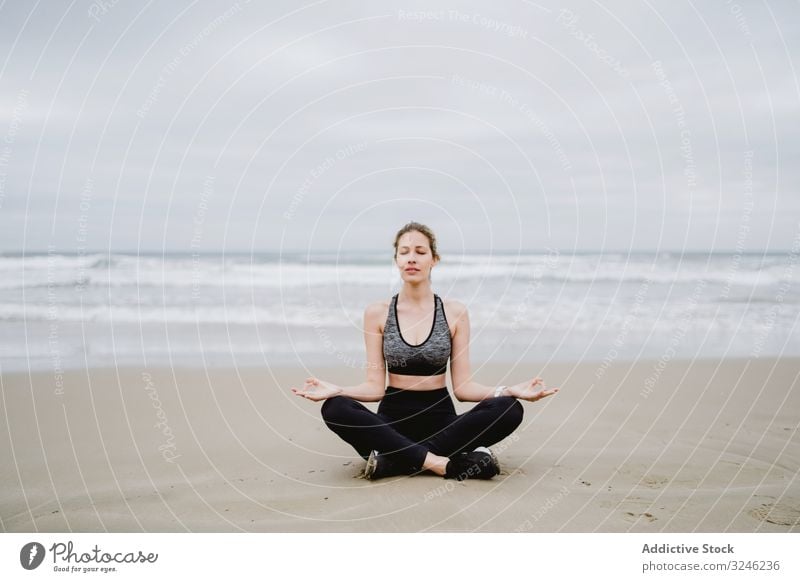 Woman meditating on the beach woman yoga practice sea ocean female exercise training workout young athlete active calm tranquility sportswear body fitness