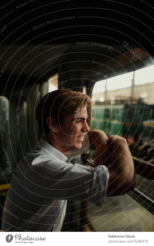 Cheerful traveler looking out train window man smile station railway rest stop transport male young retro vintage railroad trip journey commute vehicle public