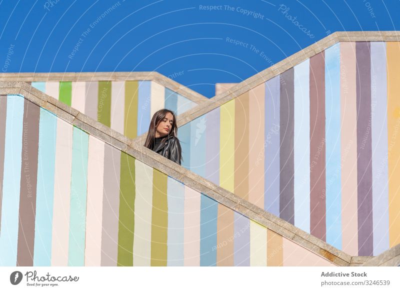 Woman standing on modern staircase woman trendy pensive serious concentrated charming gorgeous stylish glamour thoughtful wall level stairs step elegant urban