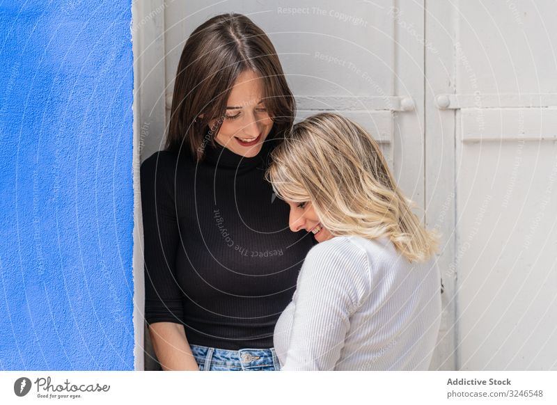 Positive women embracing in doorway girlfriends street together happy gentle tender caring friendship touch cheerful positive stylish trendy relationship