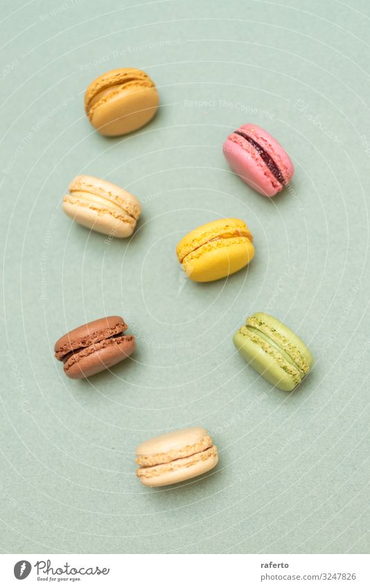 Colored tasty macaroons over a green background Dessert Gastronomy Fresh Bright Delicious Soft Yellow Green Colour Beaded Orange Purple appetizing arranged
