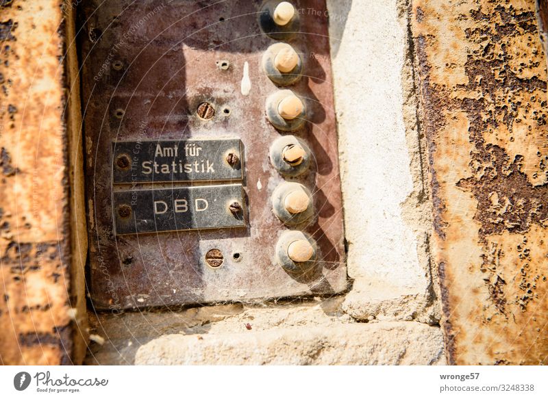Close-up of an old weathered doorbell sign on an old building with the nameplate of the Bureau of Statistics and DBD. Bell bell system bell shield Old Weathered