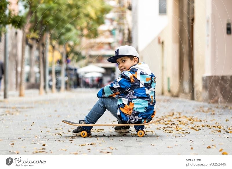 Cute little kid sitting on his sakteboard Lifestyle Style Joy Happy Beautiful Leisure and hobbies Playing Winter Sports Child School Human being Toddler