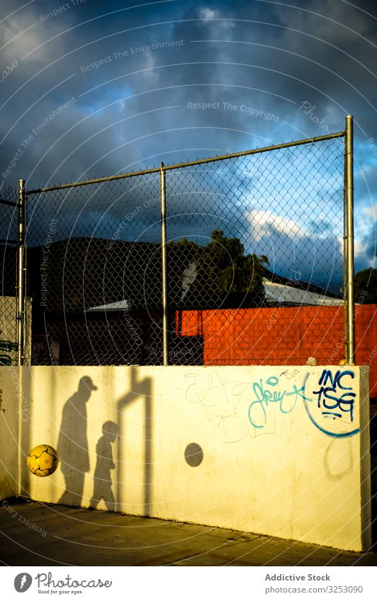 Father playing ball with son on street sports ground in twilight shadow father sunbeam cloud playground sky relax ray child rest kid colorful lush city yard