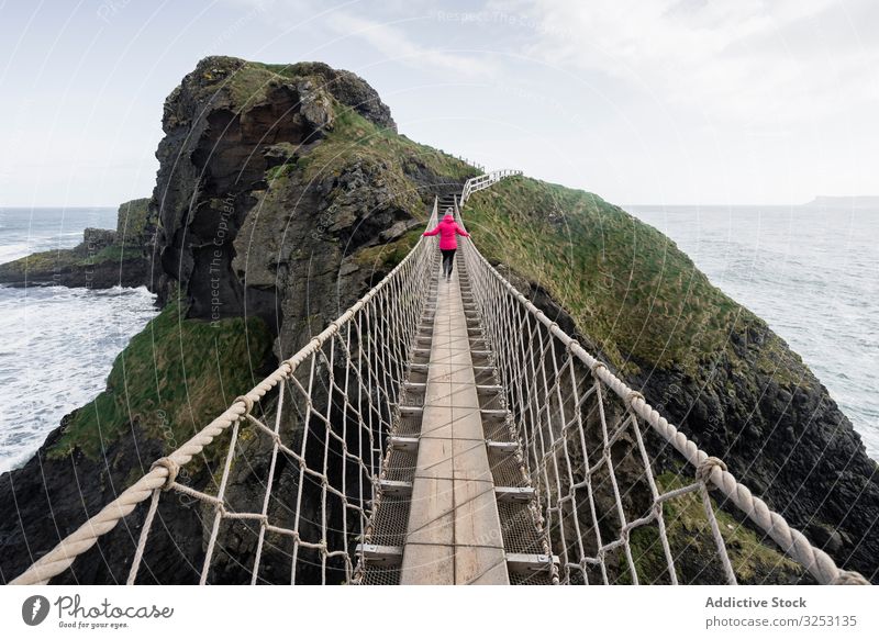 Woman crossing rope bridge leading to rocky island woman sea walk ocean northern ireland coast carric a rede shore water landscape female confidence courage