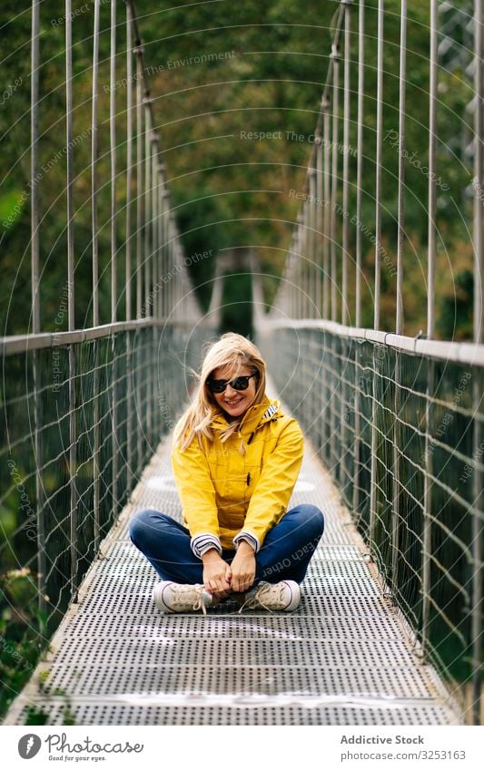 Cheerful female tourist standing on hanging bridge in summer woman footbridge forest cheerful vacation suspension summertime tourism travel journey nature