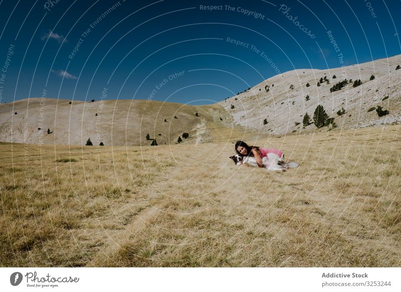 Woman playing with big dog on hill meadow woman nature travel fun playful dry happy kiss pet friend love lying landscape grass owner obedience blue sky leisure