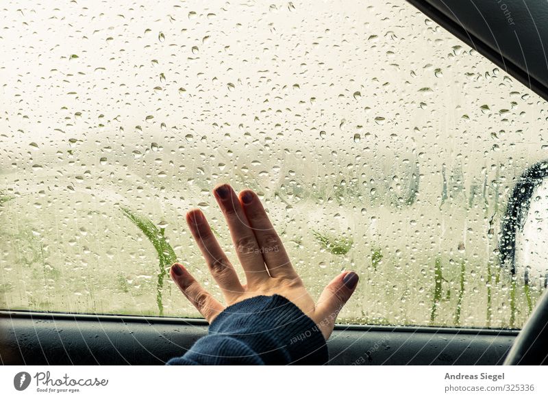 Hand wipes over steamed up car window in the rain Rain steamed-up window Car Window Slice Drops of water dreariness raindrops Bad weather melancholy