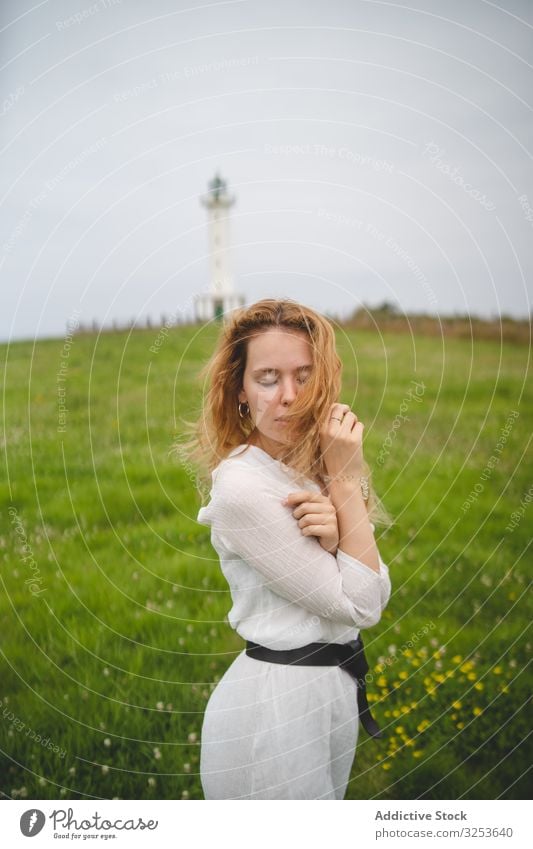 Tender woman in green field with lighthouse tender meadow gentle charming calm peaceful redhead ginger scenic nature asturias spain europe sensual silent serene
