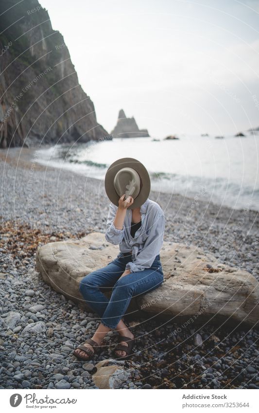 Woman resting on beach stone by sea woman bay water seascape coast shore rock calm contemplate dreaming carefree tourist enjoy relax chill traveler distance