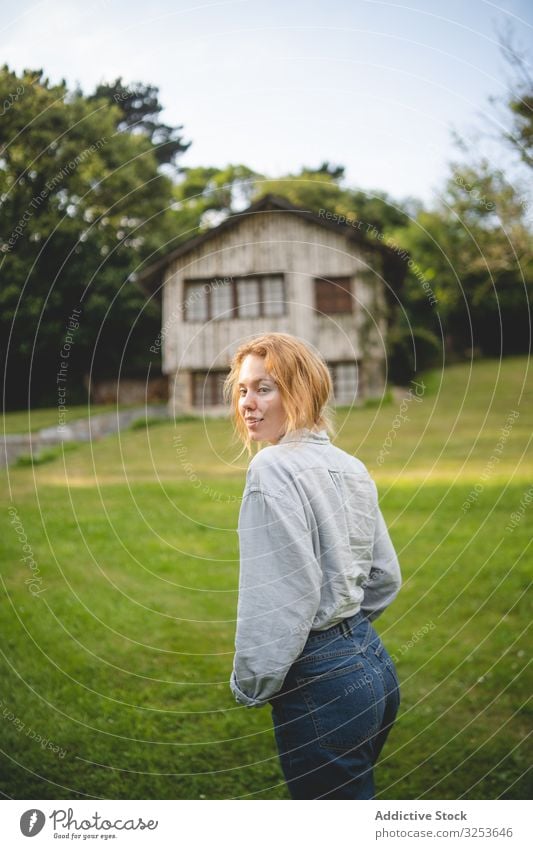 Content female walking on grass in countryside woman house enjoy field stroll meadow calm peaceful content thoughtful carefree rural village redhead ginger
