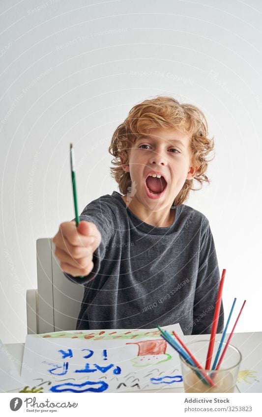 Excited boy painting at home paintbrush excited scream show art creative picture watercolor education table sit kid child tool craft study learn yell shout
