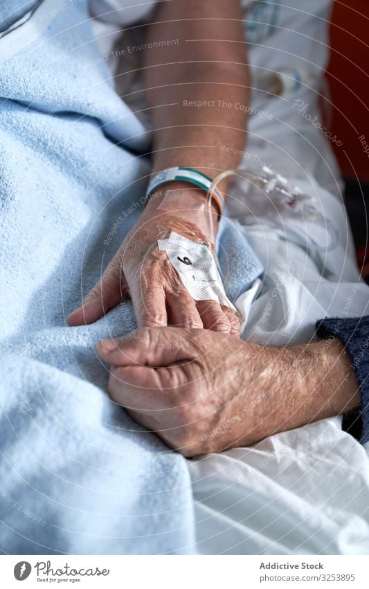 Crop senior man holding hand of sick woman in hospital couple elderly visitor patient cannula medicine healthcare bed ward mature aged wrinkle relationship