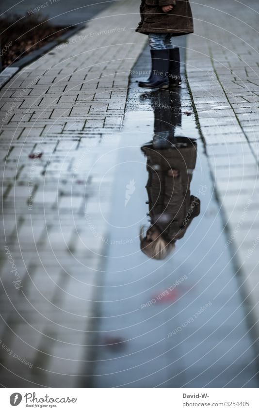 Child reflected in a puddle Girl Puddle reflection Reflection in the water Meditative Autumn somber out Gray