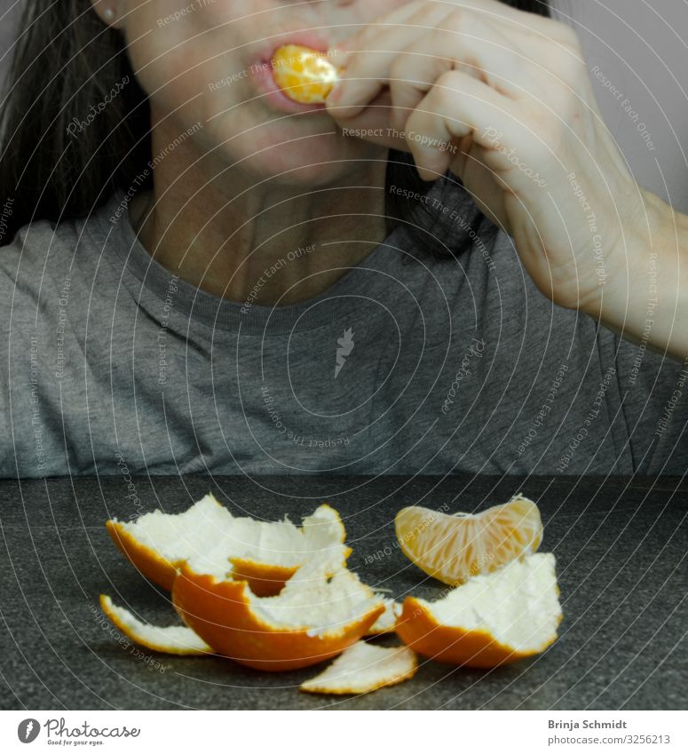 A woman shoves a piece of tangerine into her mouth Fruit Tangerine Sheath virgin fruit Eating Vegetarian diet Finger food Feminine Woman Adults Mouth To enjoy