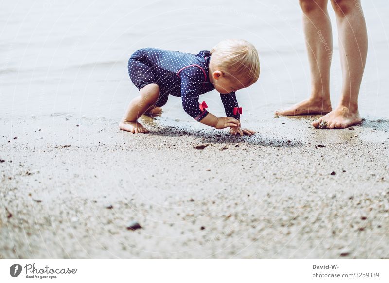 Toddler plays with sand on the beach Child Beach Sand Playing Mother foot girl Mother with child