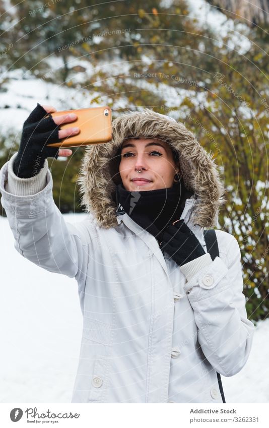 Woman taking selfie on nature at winter woman mobile phone smile content snow bush female smartphone walk rest holiday environment young happy active lifestyle