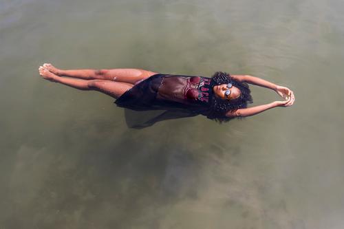 Beautiful young African woman floating at a pool of water Lifestyle Joy Relaxation Swimming pool Leisure and hobbies Playing Vacation & Travel Summer Sun Dive