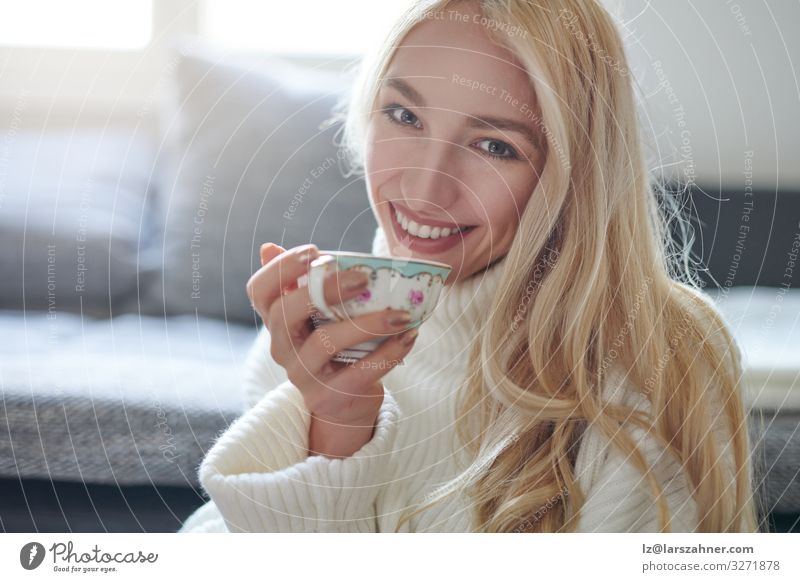 Pretty woman with long blond hair drinking tea Drinking Tea Face Winter Flat (apartment) Sofa Living room Woman Adults 1 Human being 18 - 30 years