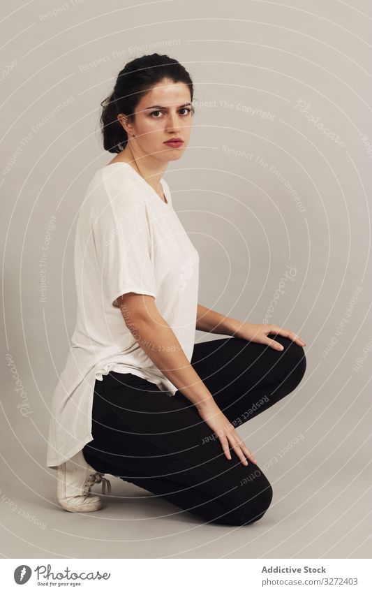 Thoughtful young woman squatting in studio thoughtful crouch appearance personality individuality complexion athletic female natural simplicity serious slim