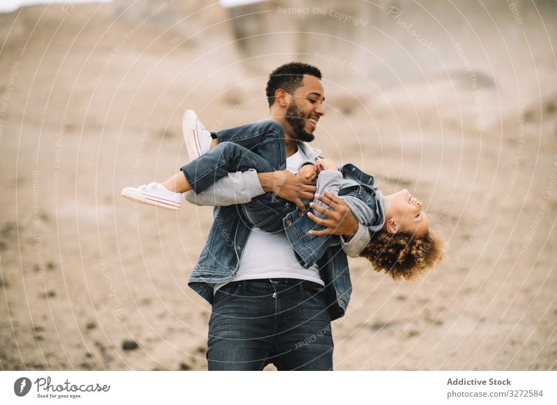 Ethnic father playing with child on ground toddler fun rest sand hill smile parent happy cheerful lifestyle modern nature dad man horizontal bonding love tender