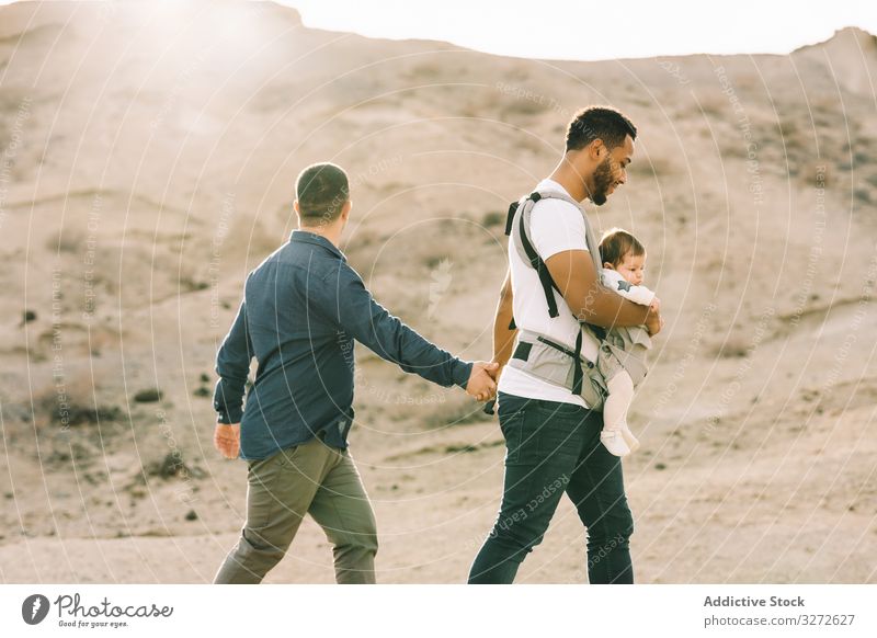 Unrecognizable diverse men walking with baby on nature gay together carrier support cuddle generation interaction lgbt homosexual stroll father male child