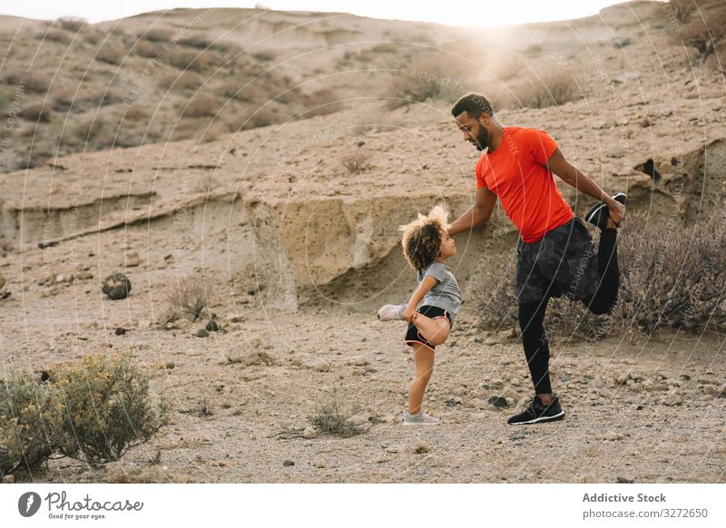 Black father preparing for sport training with child toddler stretch prepare warm up thigh teach activewear man together healthcare parent desert nature morning