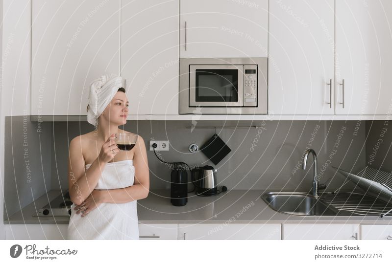 Joyful adult woman enjoying day off while having hot drink after bath in apartment with simple interior design coffee morning kitchen happy shower loft