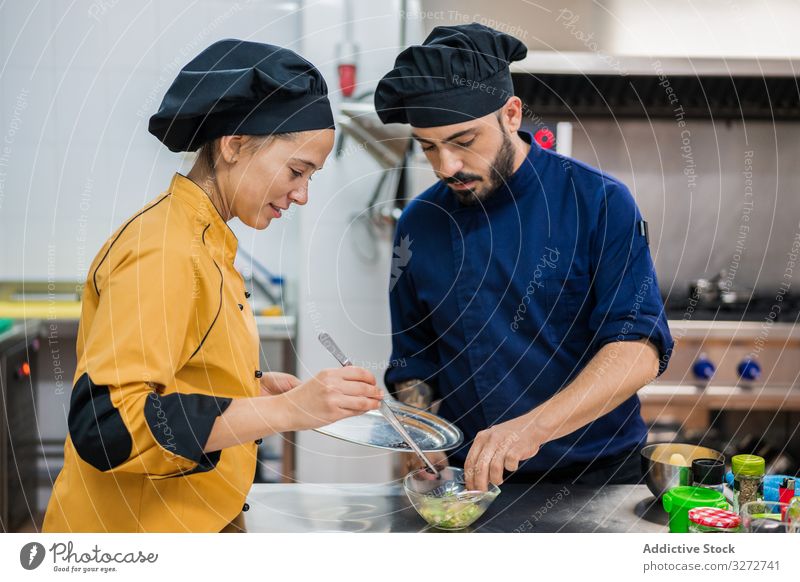 Professional chefs preparing dish in restaurant kitchen colleagues work prepare assistant professional cook food together coworker staff cooperation uniform hat