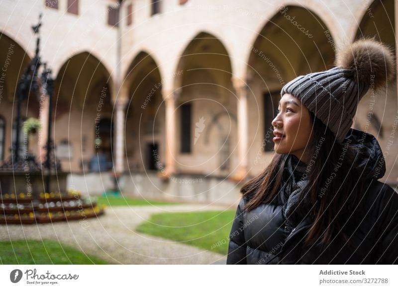 Young Asian female on vacation in warm clothing having excursion at historical temple woman sightseeing tourism old city architecture asian hat basilica