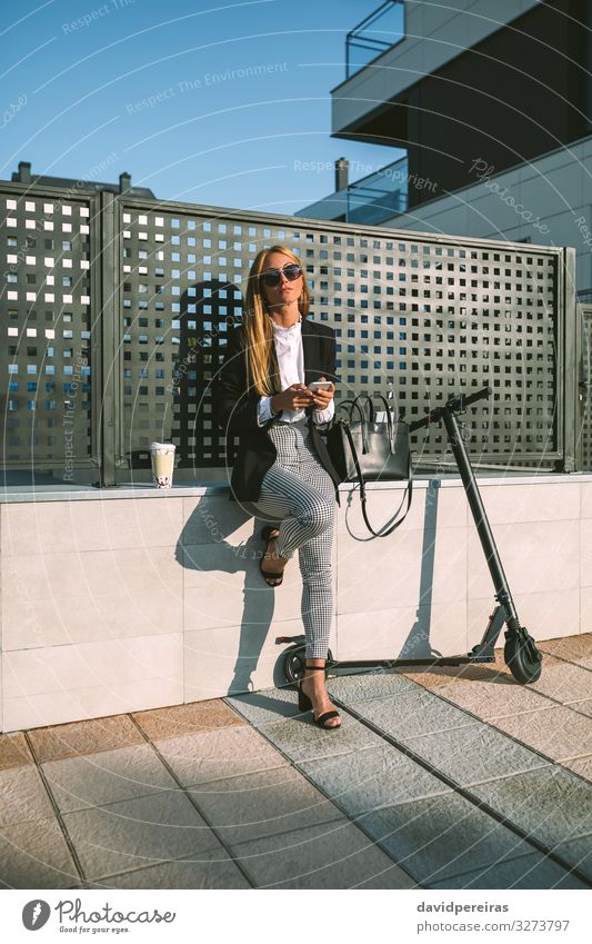 Businesswoman using mobile with her scooter next Lifestyle Style Beautiful PDA Human being Woman Adults Street Fashion Sunglasses Sit Wait Modern attractive