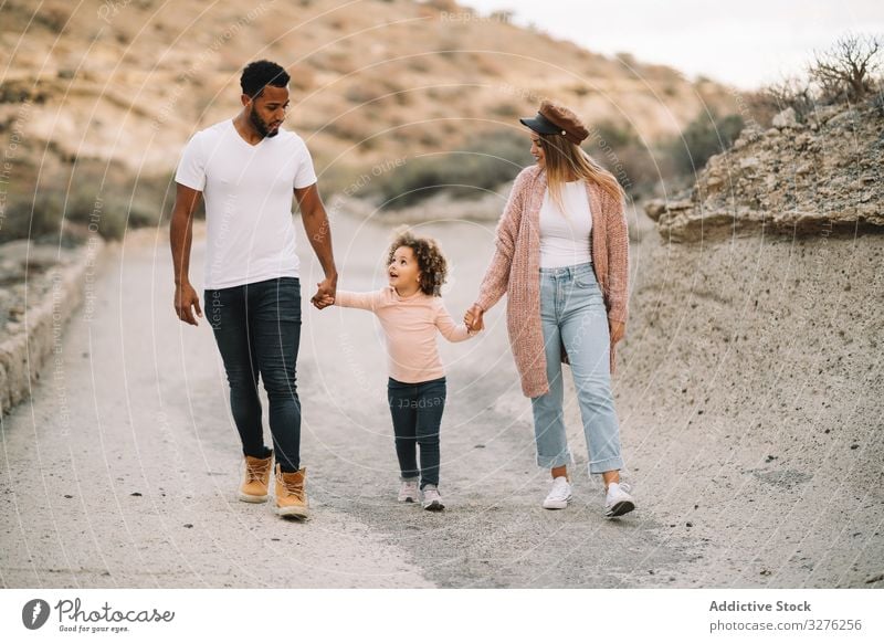 Stylish multiethnic family walking on nature hold hands together parent toddler rest smile happy stroll cheerful lifestyle modern child man bonding love tender