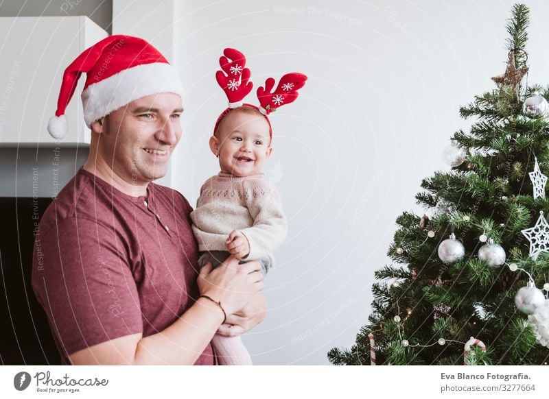 Happy father with baby girl playing at home with reindeer diadem. Christmas concept Father Parents parenthood Smiling Hold Playing Santa Claus Mother motherhood