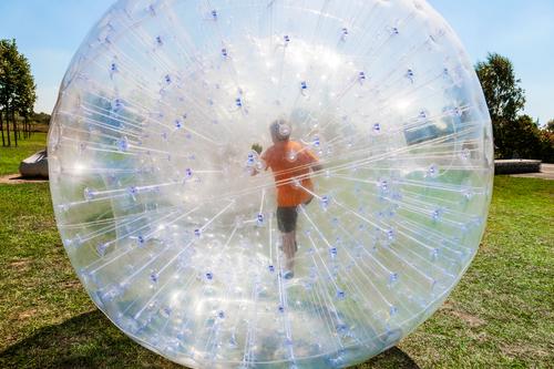 children have fun in the Zorbing Ball Joy Happy Leisure and hobbies Adventure Summer Sun Sports Child Grass Meadow Hill Sphere Drop Movement Fitness Laughter