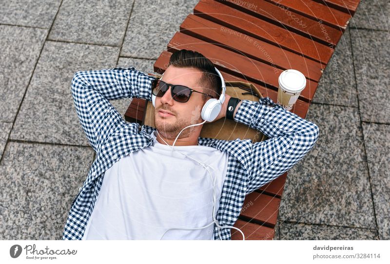 Man with headphones lying on a bench Lifestyle Relaxation Leisure and hobbies Entertainment Music Work and employment Technology Internet Human being Adults