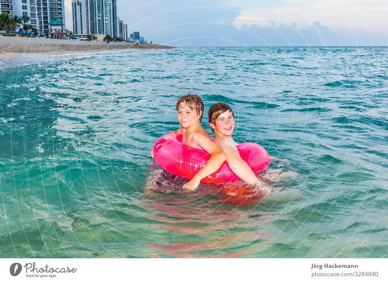 brothers in a swim ring have fun in the ocean Joy Happy Beautiful Skin Relaxation Leisure and hobbies Vacation & Travel Sun Ocean Waves Child Boy (child)