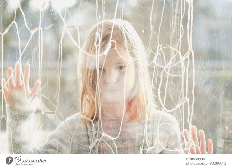 Girl standing behind a pane of glass Playing Living or residing Fairy lights girl 1 Human being 3 - 8 years Child Infancy Observe Dream Sadness Bright natural