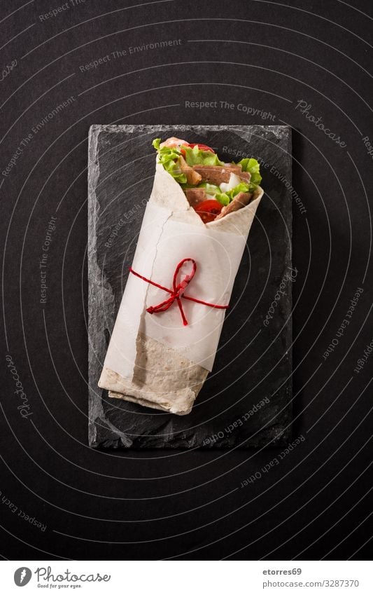 Doner kebab or shawarma sandwich on black slate background. doner Kebab Sandwich Wrap Meat Roll Chicken Vegetable Tomato Lettuce Onion Herbs and spices Sauce