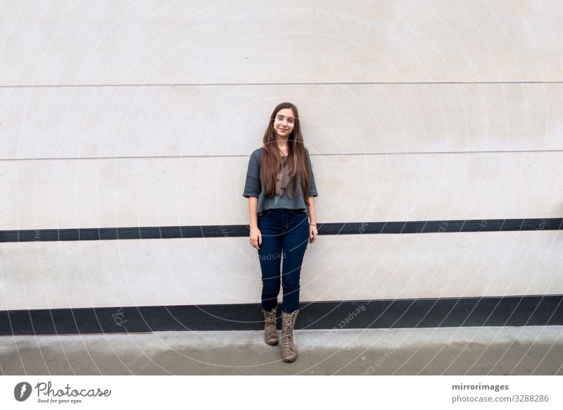 woman standing with back toward a big city building wall Young woman Youth (Young adults) Body Head 1 Human being Wall (barrier) Wall (building) Jeans Boots