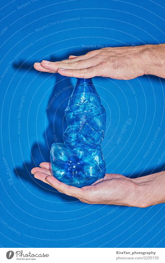 Two hands squeezing plastic bottle on blue background Bottle Lifestyle Shopping Save Beach Ocean Industry Hand Environment Packaging Plastic Simple Free Blue