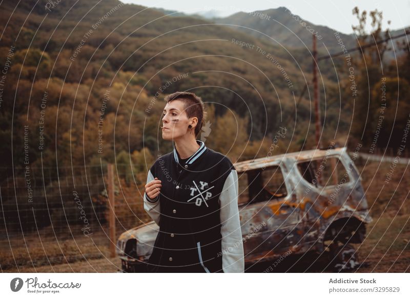 Woman with cigarette walking near burnt car woman smoke rebel rest rusty countryside young lean lifestyle freedom vehicle auto androgynous short hair subculture