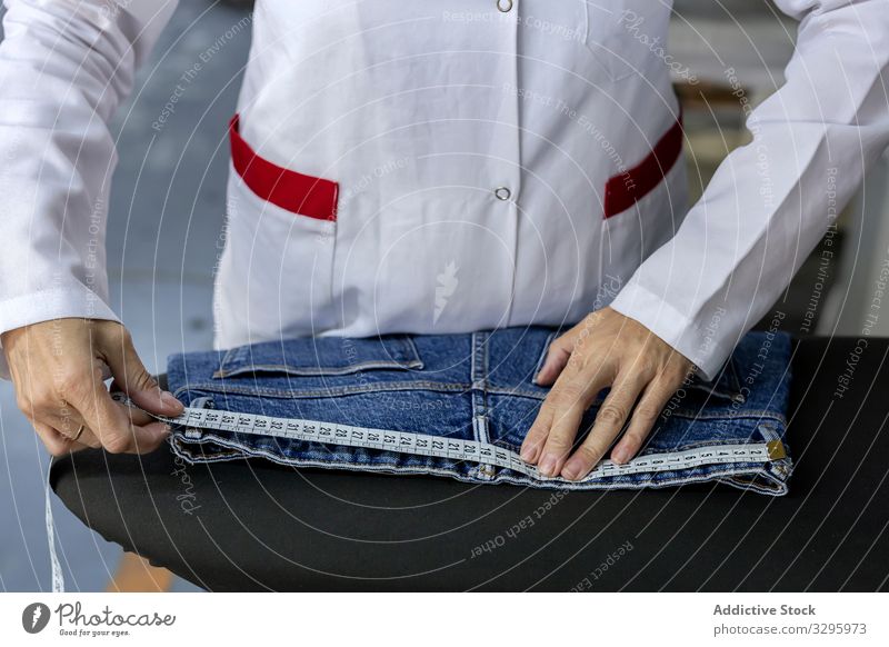Woman's hands in textile factory ironing on industrial sewing machine. industry clothing manufacturing worker woman fabric pants blue jeans occupation