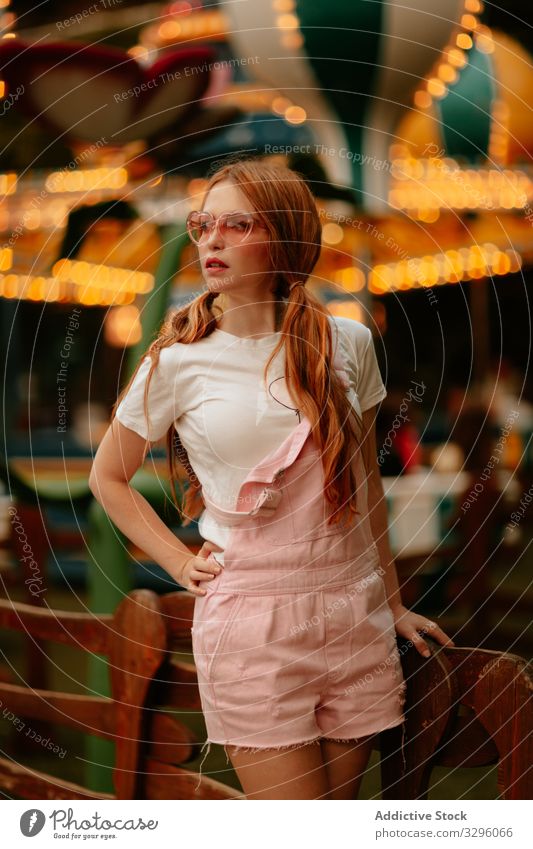 Stylish teenage girl standing in amusement park woman style fashion teenager trendy sensual jumpsuit millennial relax female enjoy young careless childish