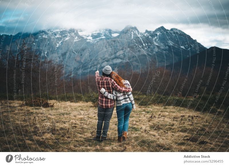 Charming red haired woman embracing man in mountains with closed eyes couple hugging bonding amorous romantic relationship lawn travel adventure tender