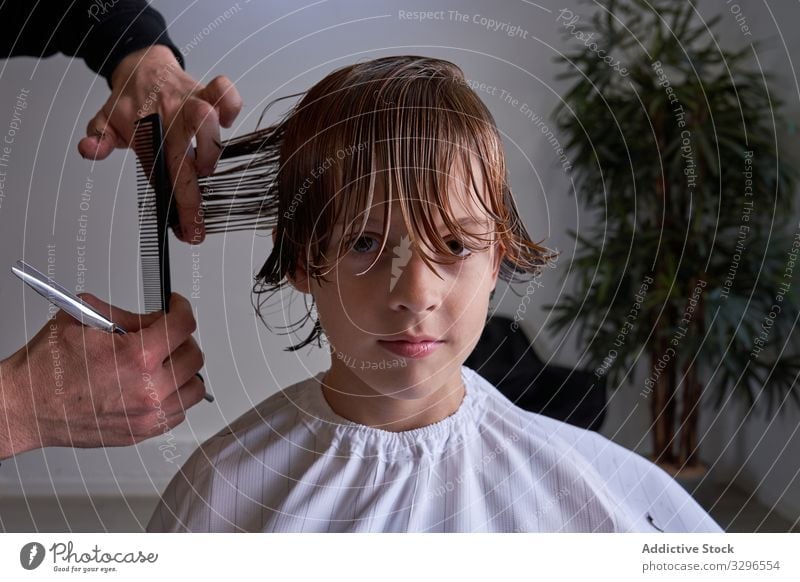Boy cutting his hair at a hairdresser's barber barbershop child young kid fashion salon hairstyle trimming boy female haircut sitting beauty popular chair