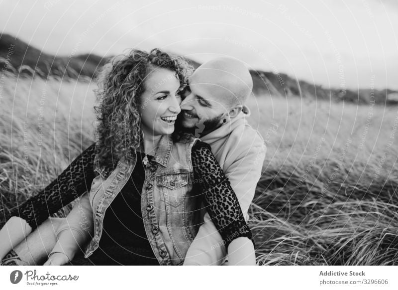 Hipster couple in love sitting in field and enjoying romantic moments embrace nature happy young together grass hug cuddle romance relationship tenderness