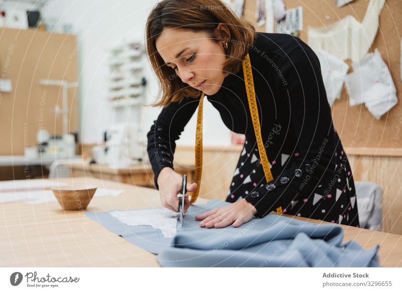 Dressmaker cutting cloth on table dressmaker fabric detail woman scissors work workshop fashion tailor clothing textile female designer professional garment