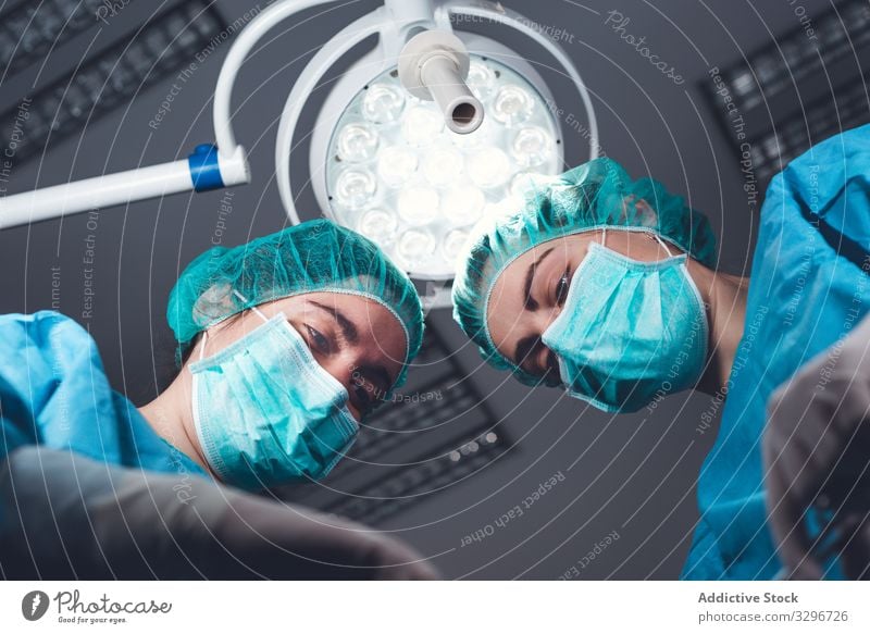 Women performing surgery in hospital together surgeon operating theater lamp tool mask hat women work doctor healthcare female sterile instrument colleague job
